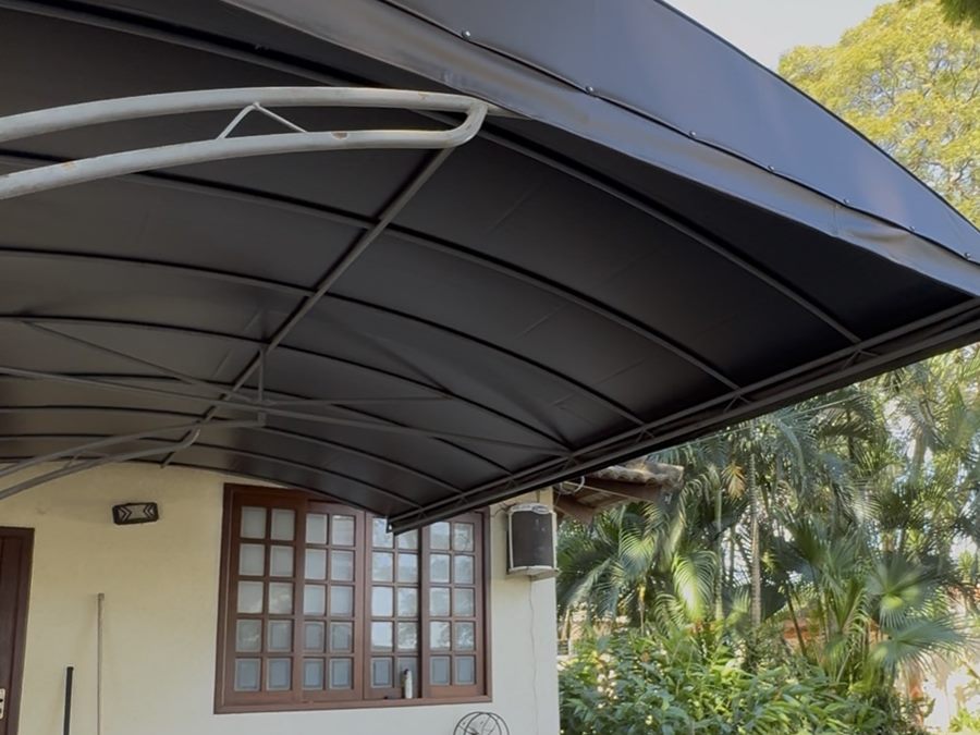 Toldo curvado em lona preta sobre a entrada de uma residência