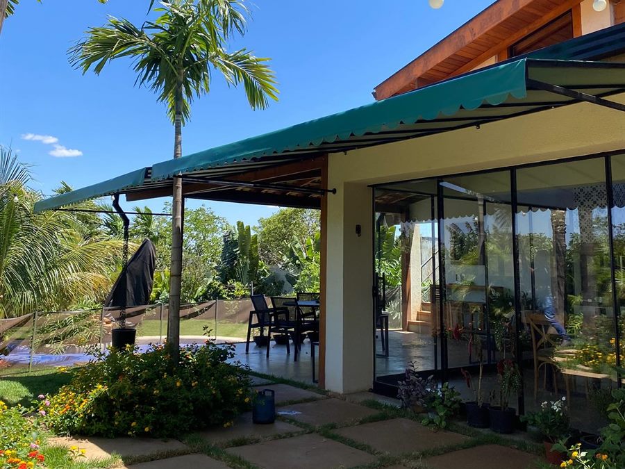 Toldo em lona verde sobre a varanda de uma casa com piscina